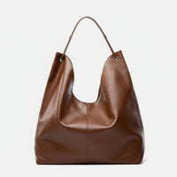 Large brown leather tote bag with single handle on white background