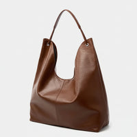 Brown leather tote bag with single handle on white background