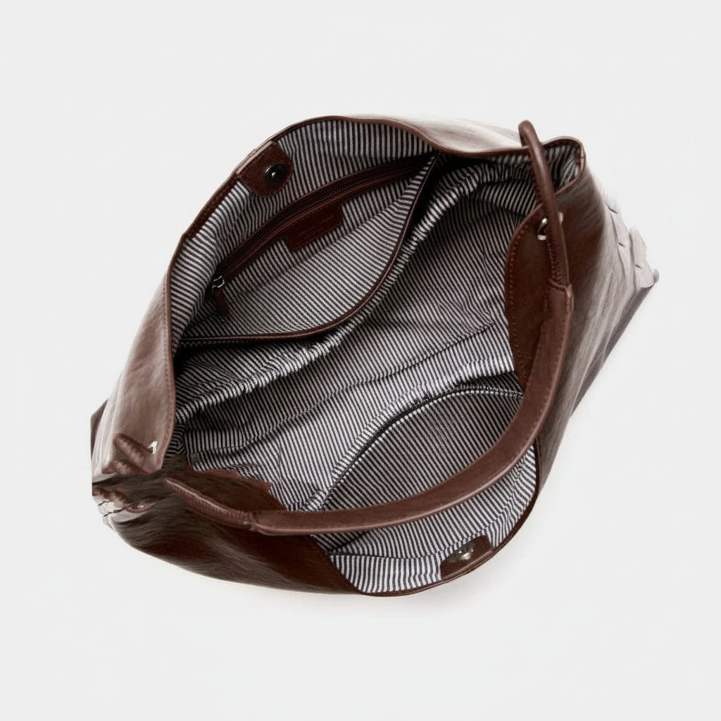 Open brown leather tote bag with striped interior and snap closures
