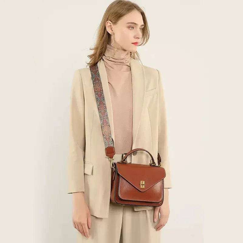 Woman in beige suit carrying brown leather crossbody handbag with patterned strap