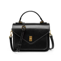 Black leather crossbody handbag with gold hardware and top handle on white background