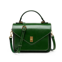 Green leather handbag with gold hardware, top handle, and shoulder strap on white background