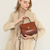 Woman in beige suit holding a brown leather handbag with gold clasp