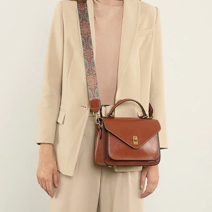 Woman in beige suit carrying brown leather crossbody satchel with patterned strap