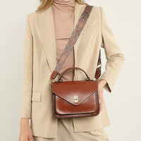 Woman in beige suit with brown leather crossbody bag and patterned strap