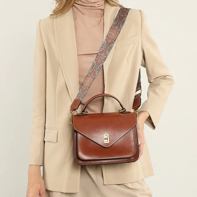 Woman in beige suit with brown leather crossbody bag and patterned strap