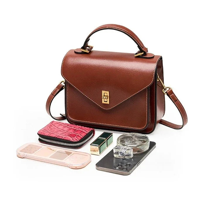Brown leather crossbody handbag with accessories, wallet, makeup, phone, and perfume bottle
