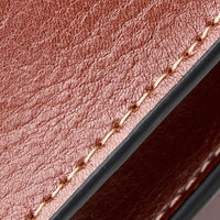 Close-up of brown leather wallet with detailed stitching and textured surface