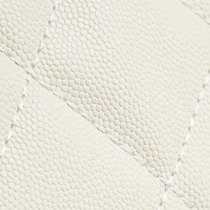 Close-up of cream quilted lizard-embossed leather with visible stitching detail
