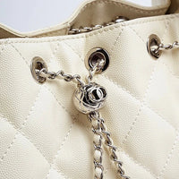 Close-up of cream quilted leather handbag with silver chain and metal grommet details