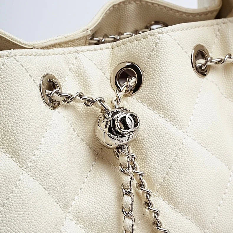 Close-up of cream quilted leather handbag with silver chain and metal grommet details