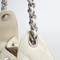 Close-up of white leather quilted handbag with silver chain strap and textured finish