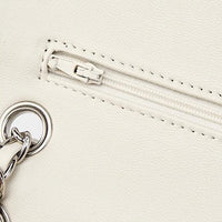 Close up of white faux leather bag with silver zipper and chain detail