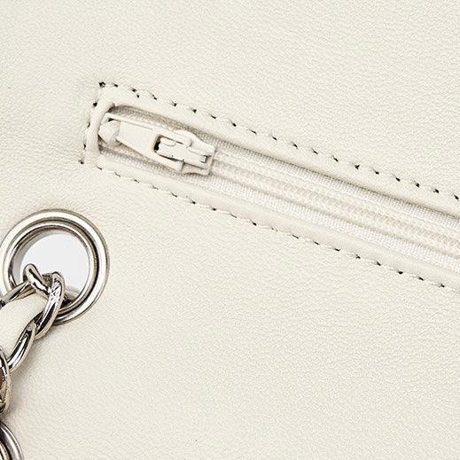 Close up of white faux leather bag with silver zipper and chain detail