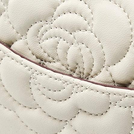 Beige leather bag with quilted floral stitching and a curved seam detail