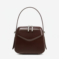 Brown leather handbag with top handle and silver zippers on white background