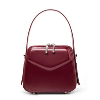 Burgundy leather handbag with structured shape and top handle on white background