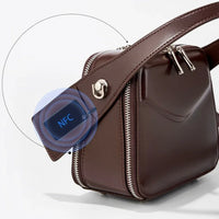Brown leather shoulder bag with visible NFC chip on strap and dual silver zippers