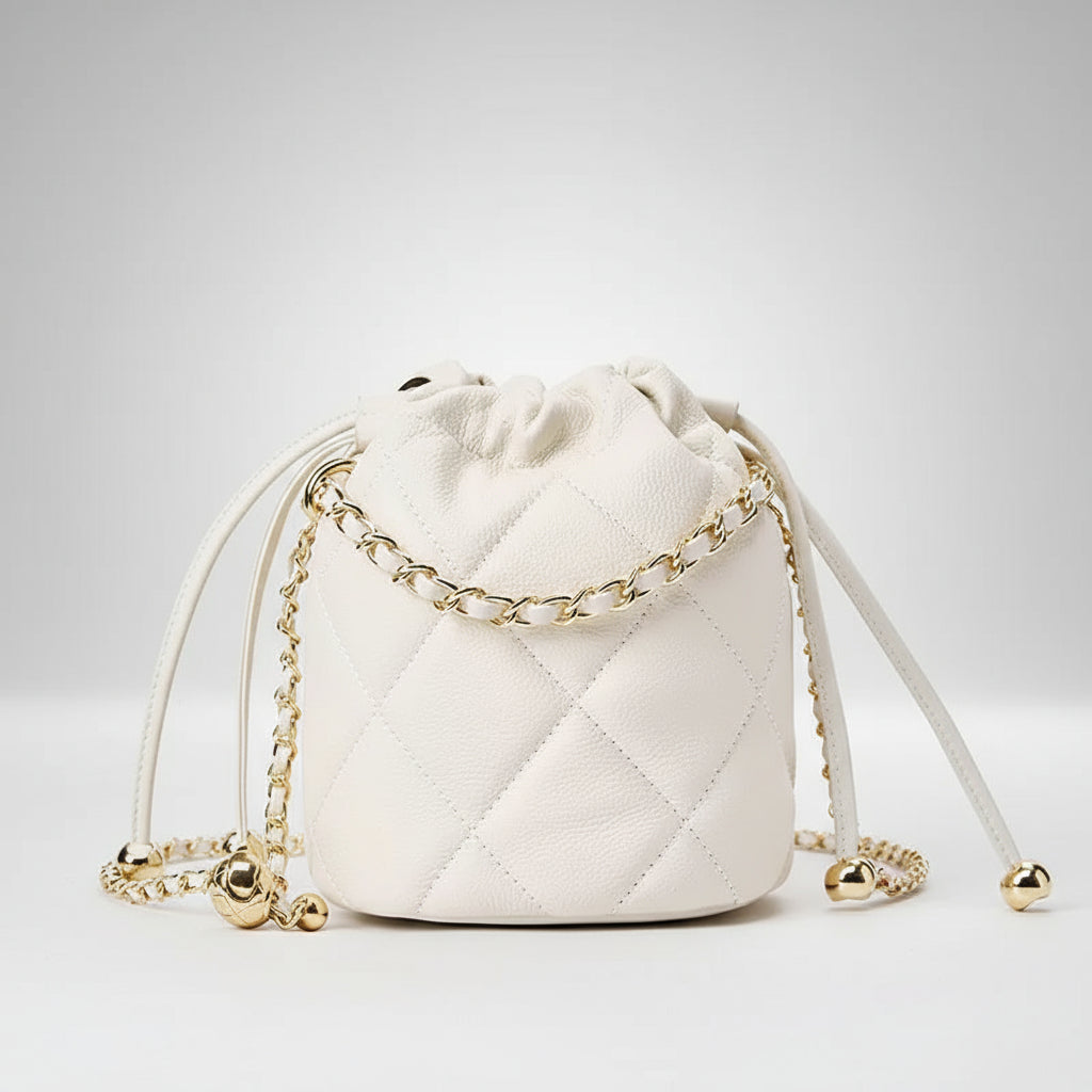 White quilted drawstring bucket bag with gold chain strap and gold accents on a white background.