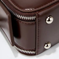 Close-up of brown leather bag corner with metal studs and silver zipper detail
