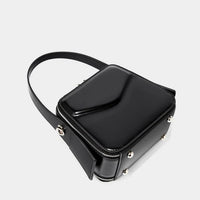 Black square leather crossbody bag with silver studs and zipper on white background