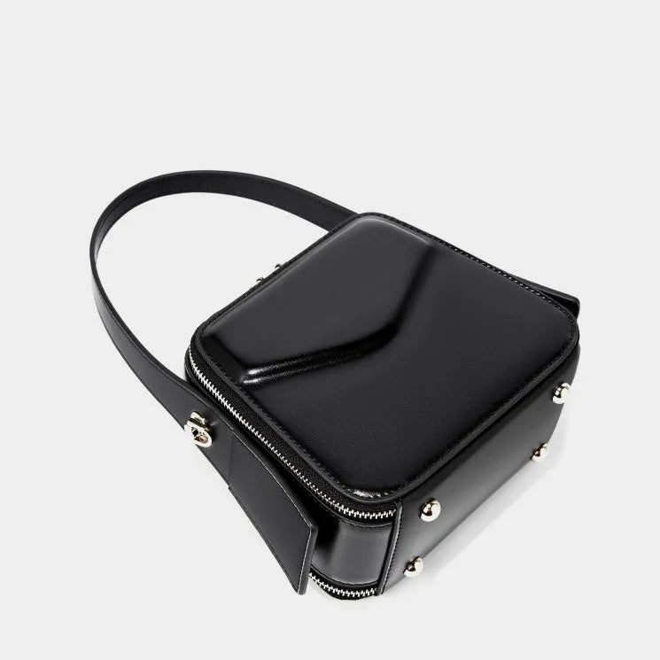 Black square leather crossbody bag with silver studs and zipper on white background
