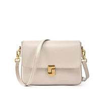 Beige leather crossbody bag with gold hardware and a front clasp on white background