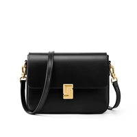 Black leather crossbody bag with gold clasp and hardware on white background