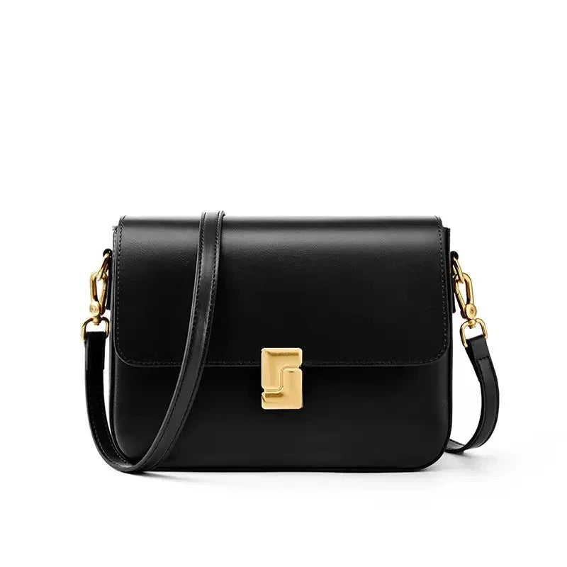 Black leather crossbody bag with gold clasp and hardware on white background