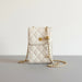 Cream quilted crossbody bag with gold chain strap and flower detail held by hand