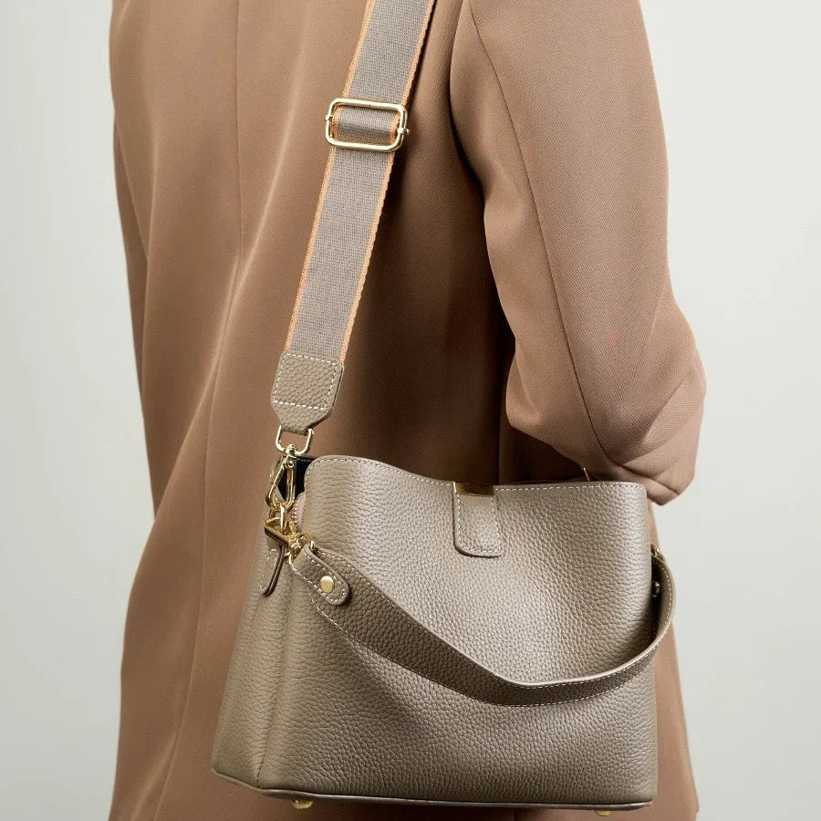 Taupe leather shoulder bag with gold hardware on beige blazer