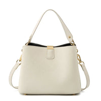 Beige leather handbag with gold hardware and detachable shoulder strap on white background