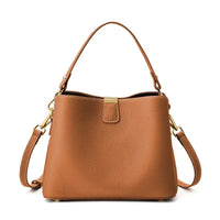 Tan leather handbag with gold hardware and detachable shoulder strap on white background