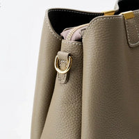 Taupe leather handbag closeup with gold hardware and pebbled texture