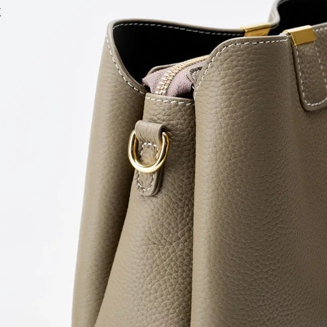 Taupe leather handbag closeup with gold hardware and pebbled texture