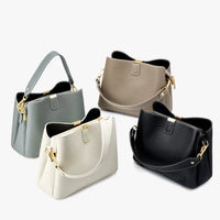 Set of four leather handbags in black, gray, beige, and cream with gold hardware on white background