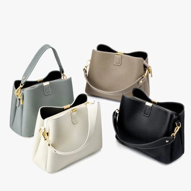 Set of four leather handbags in black, gray, beige, and cream with gold hardware on white background
