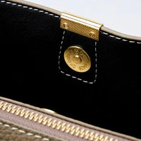 Close-up of gold magnetic snap and zipper on leather handbag interior with contrast stitching