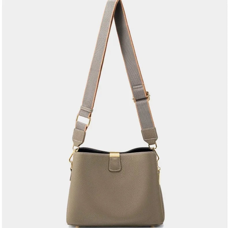Taupe leather crossbody bag with wide adjustable strap and gold hardware on white background