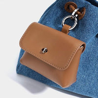 Small tan leather pouch keychain on a blue denim fabric background