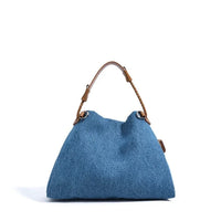Blue denim tote bag with brown leather handle on white background