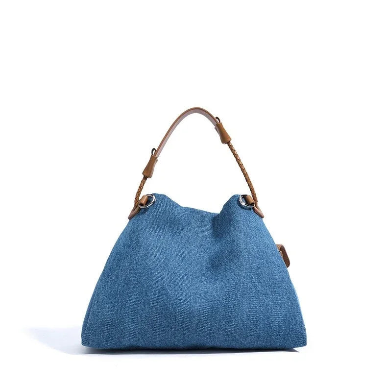 Blue denim tote bag with brown leather handle on white background