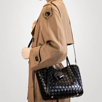 Woman in tan trench coat carrying black woven leather shoulder bag