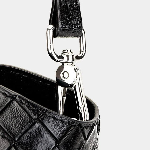 Black leather quilted bag with silver hardware and clasp detail on a light background