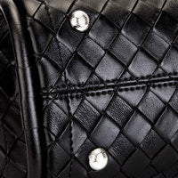 Close-up of black woven leather bag with silver rivets and visible stitching detail