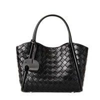 Black woven leather tote bag with dual handles and attached decorative tag