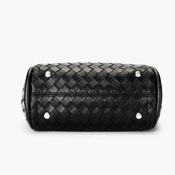 Black woven leather handbag bottom with metal feet on white background