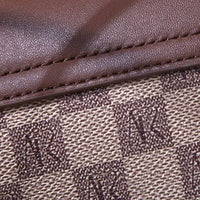 Close-up of brown leather and checkered canvas with repeating AR monogram pattern