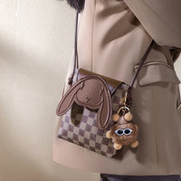 Woman wearing checkered brown crossbody bunny purse with plush keychain accessory