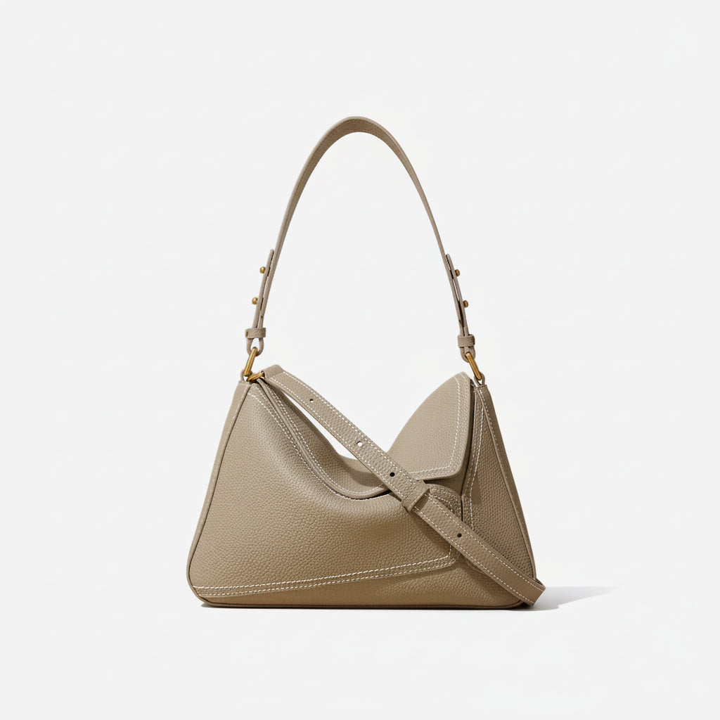 Taupe leather shoulder bag with gold hardware and top handle on neutral background